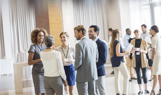 Group of business people stood together discussing plans smiling